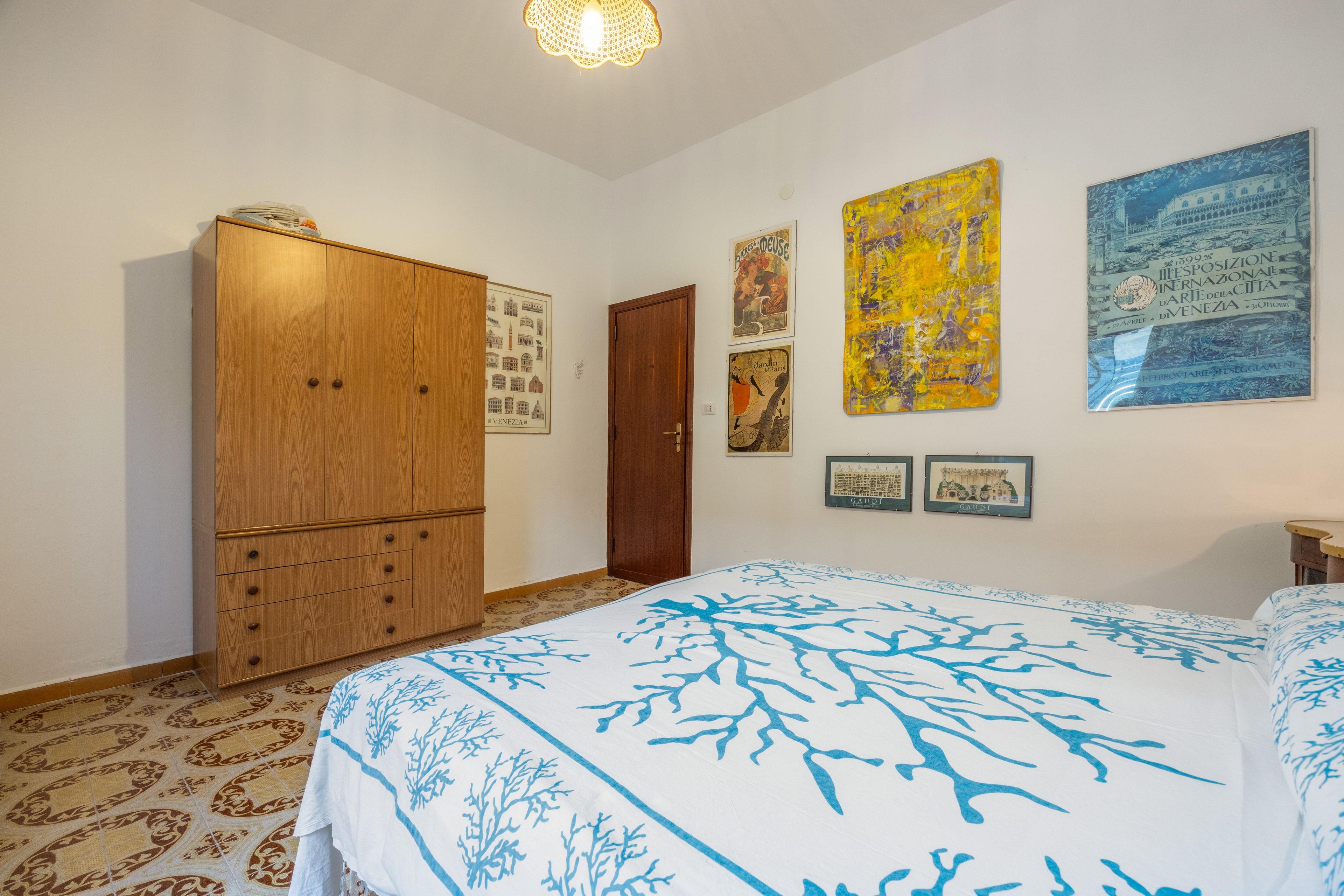 Ein Schlafzimmer mit einem großen Bett, einem Kleiderschrank und verschiedenen gerahmten Kunstwerken an der Wand.
