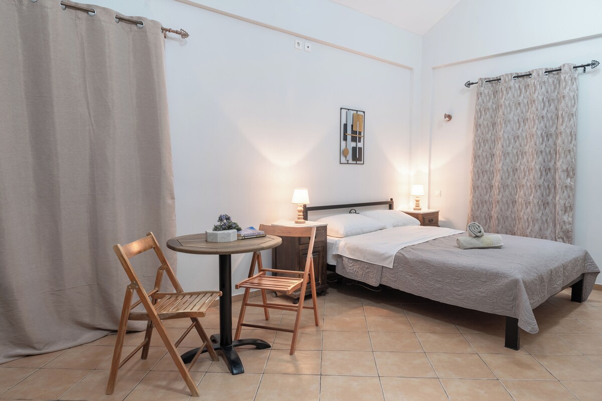 Ein Hotelzimmer mit einem Bett, einem Tisch, zwei Stühlen, einer Lampe und einem Gemälde an der Wand.