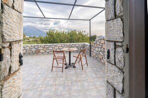 Eine Terrasse im Freien mit Steinmauern, einem runden Tisch und zwei Holzsesseln.