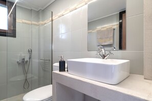 Ein modernes Badezimmer mit einem weißen Waschbecken, einer Duschkabine aus Glas und einer Toilette.
