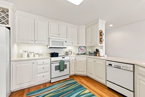 A kitchen with white cabinetry, a microwave, an oven, a dishwasher, and a colorful rug. - 1524 Front Street-Sound Front with Dock (Beaufort)