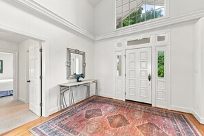 A spacious room with a large rug, a mirror, a desk, and a set of double doors. - 1524 Front Street-Sound Front with Dock (Beaufort)