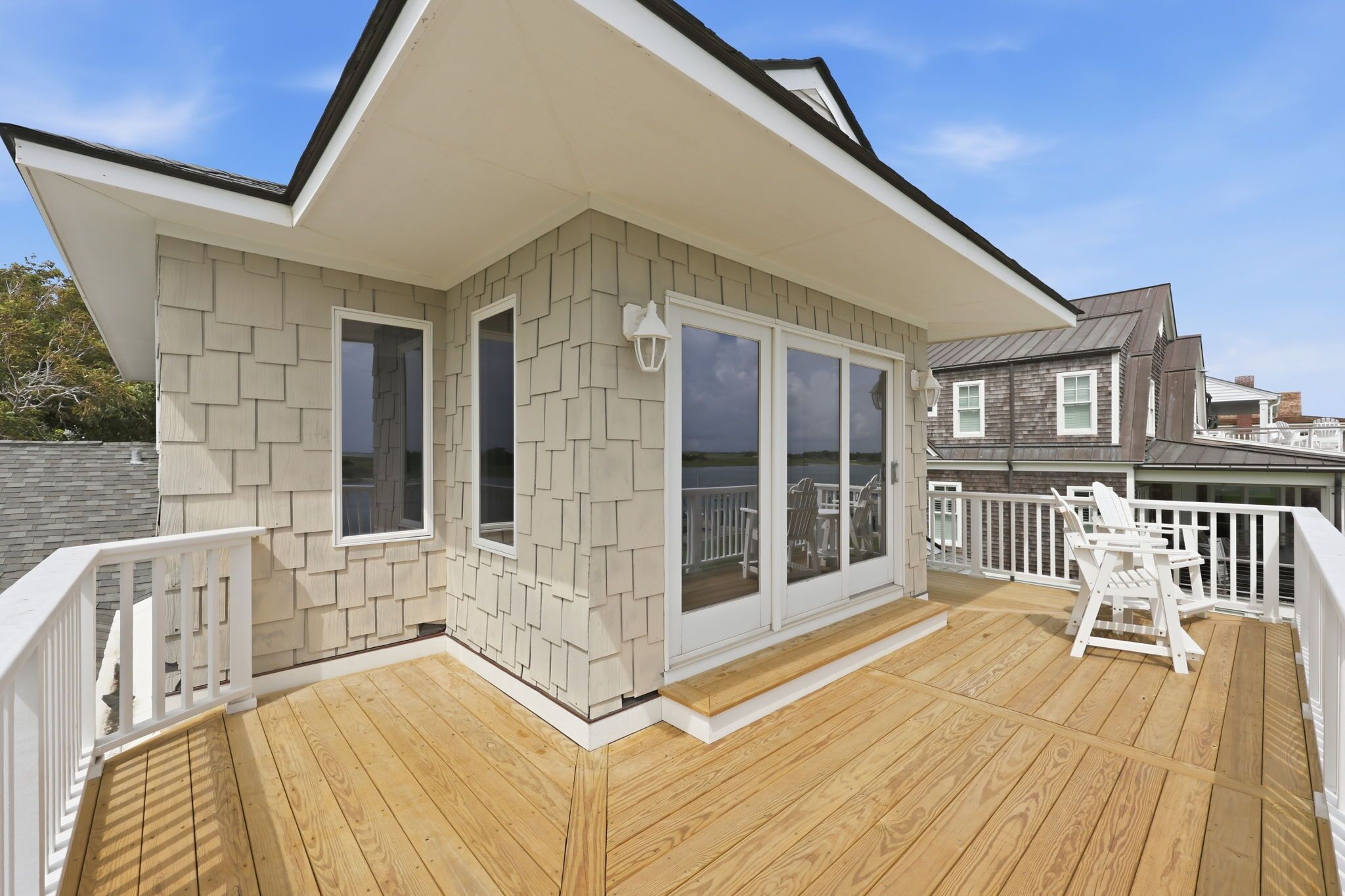 A deck with a railing, a covered area with a door, and a view of the water.