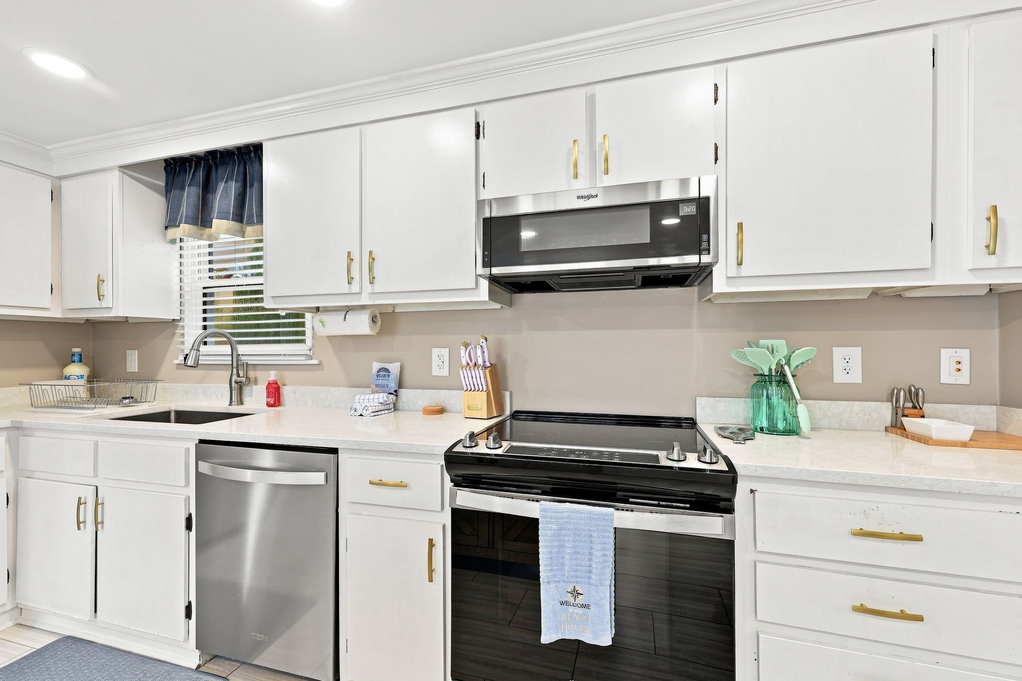 A modern kitchen with white cabinetry, stainless steel appliances, and a built-in oven.
