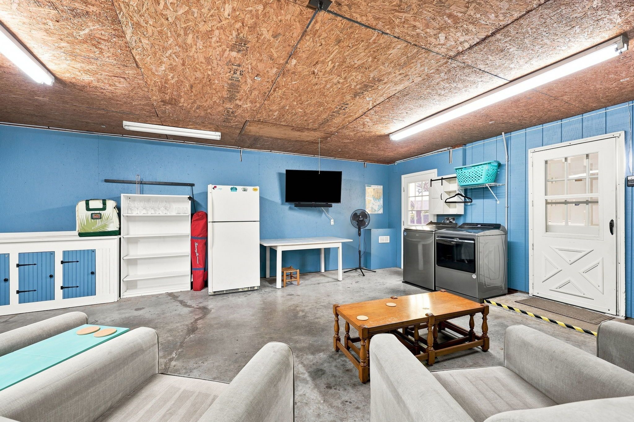 A compact room with a kitchenette, a television, and seating.