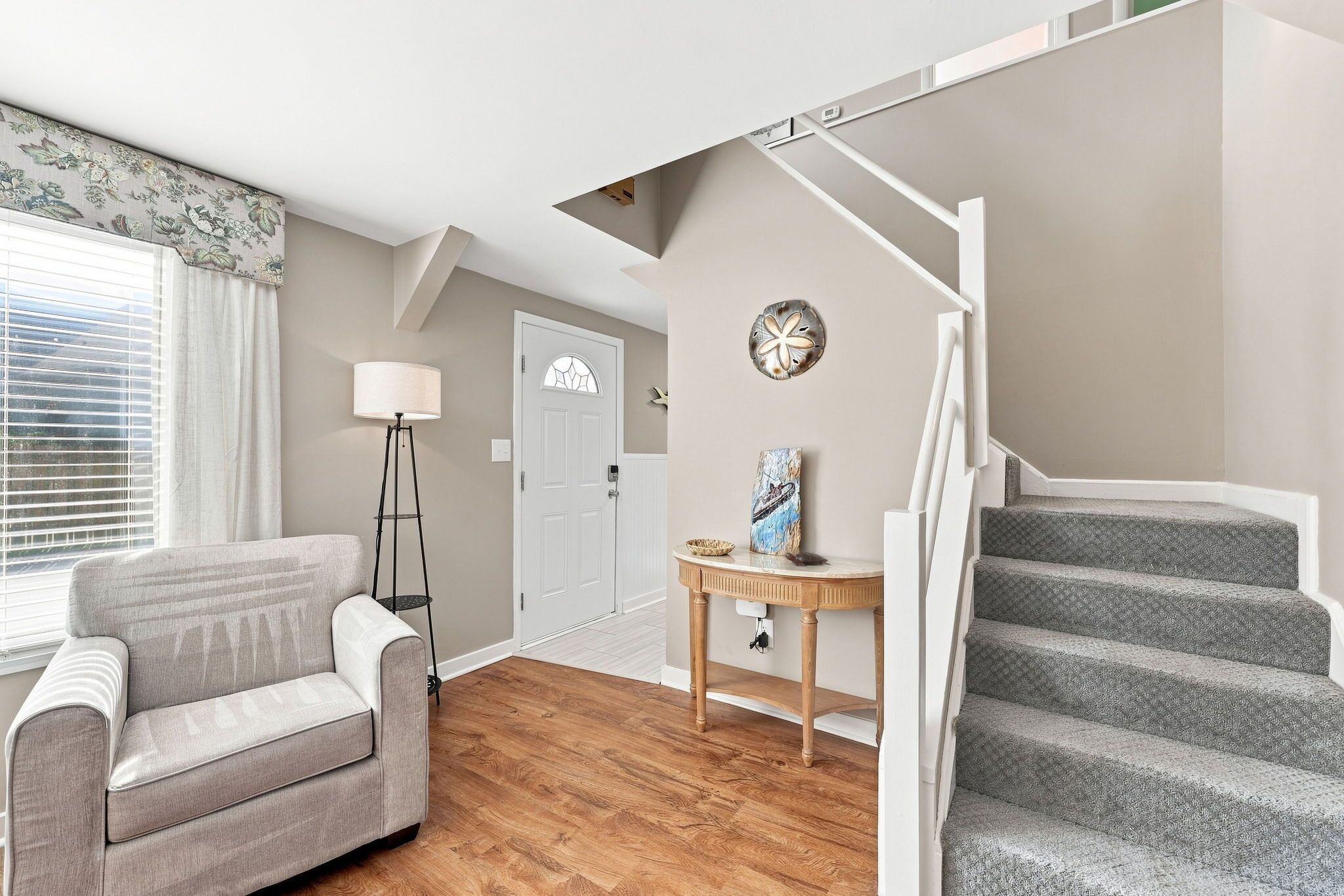 A living room with a sofa, a lamp, a table with a decorative item, and a staircase.