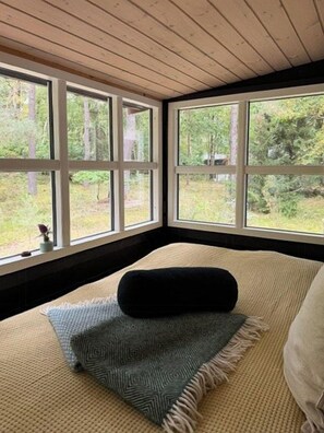 Ein Zimmer mit einem Bett, einem Fenster und Blick auf einen Wald.