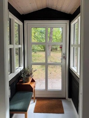 Een kamer met een bank, een deur en uitzicht op het landschap.