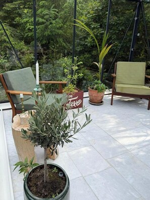 Eine Terrassenfläche mit zwei Stühlen, einem Topfpflanzen und einem Schild mit dem Wort 'Love'.