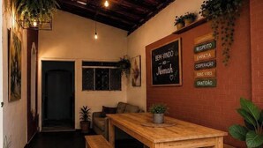 A cozy interior with a wooden table, a chalkboard with inspirational words, and a brick wall. - Nomah Hostel 2 (São José do Rio Preto)
