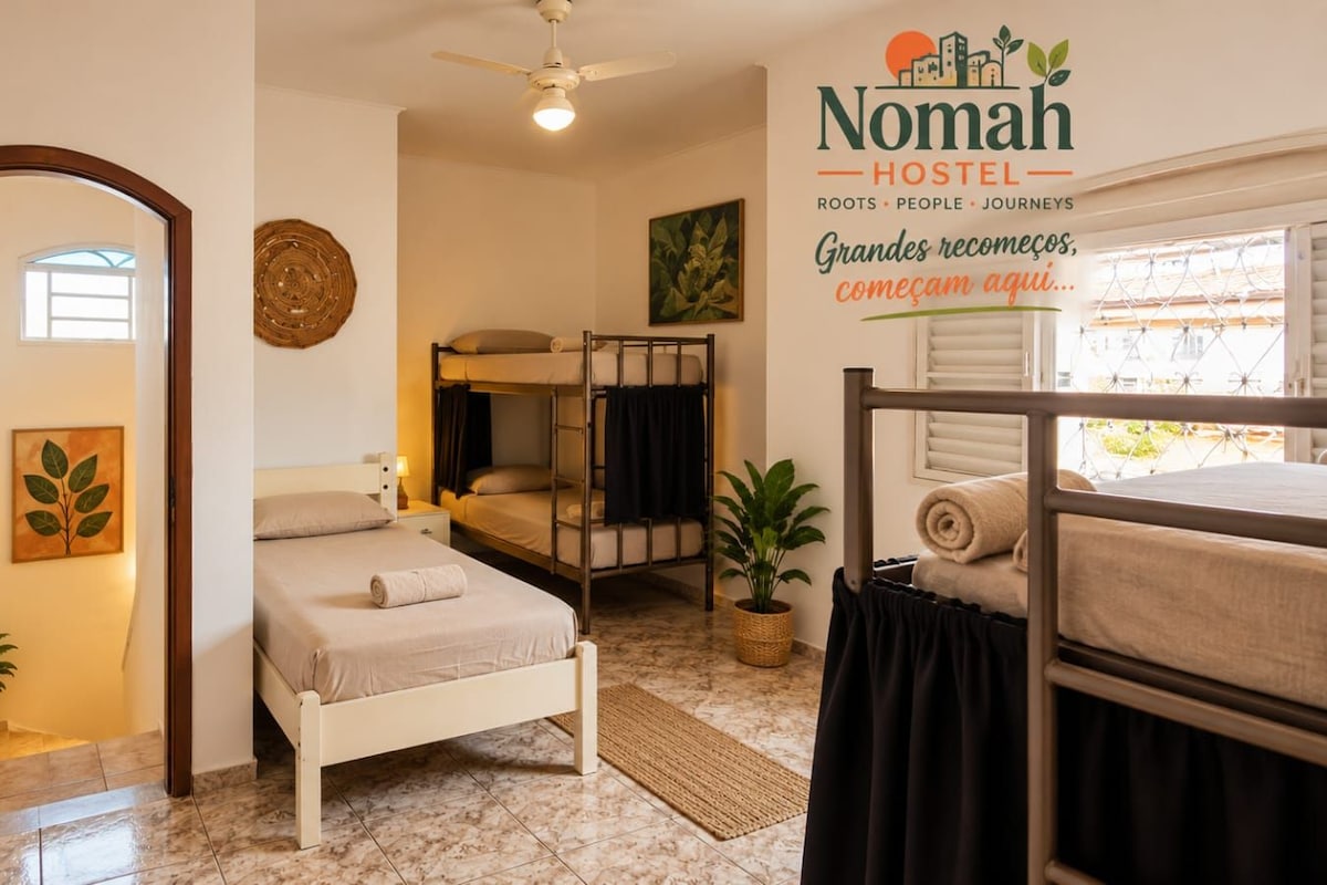 A hostel room with bunk beds, a single bed, a ceiling fan, and a wall-mounted sign.