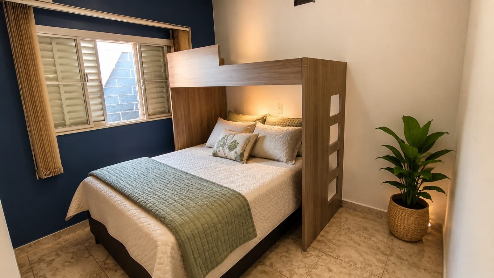 Una cama individual con cabecera de madera, una mesita de noche, una planta en maceta y una ventana con persianas.