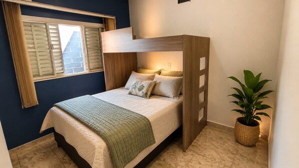 A bunk bed with a wooden headboard, a bedside table, a potted plant, and a window with blinds. - Nomah Hostel 2 (São José do Rio Preto)