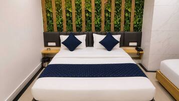 A hotel room with a bed, a bedside table with a phone, a trash bin, and a wall with vertical greenery.