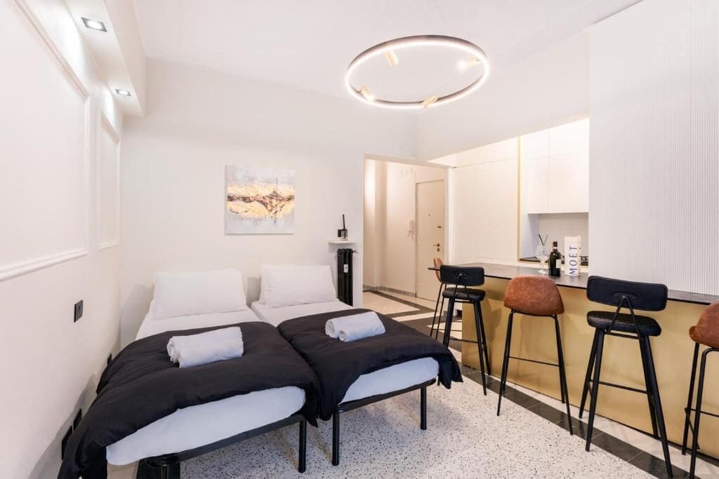 Ett hotellrum med två sängar, ett litet kök och en barhörna.