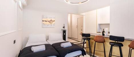 Ett hotellrum med två sängar, ett litet kök och en barhörna.