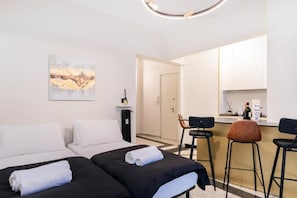 A hotel room with two beds, a kitchenette, and a bar area. - Luciano Luxury Apartment (Roma)
