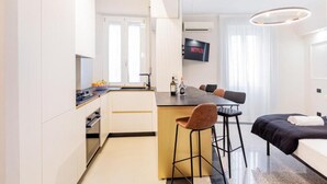A modern hotel room with a kitchenette, a dining area, and a bed. - Luciano Luxury Apartment (Roma)