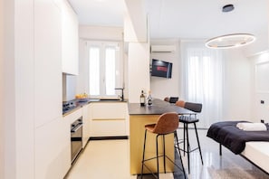 A modern hotel room with a kitchenette, a dining area, and a bed. - Luciano Luxury Apartment (Roma)