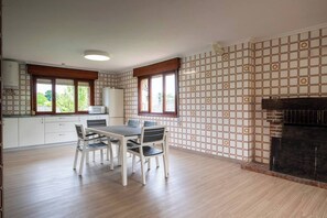A spacious kitchen with a dining area, large windows, and a fireplace.