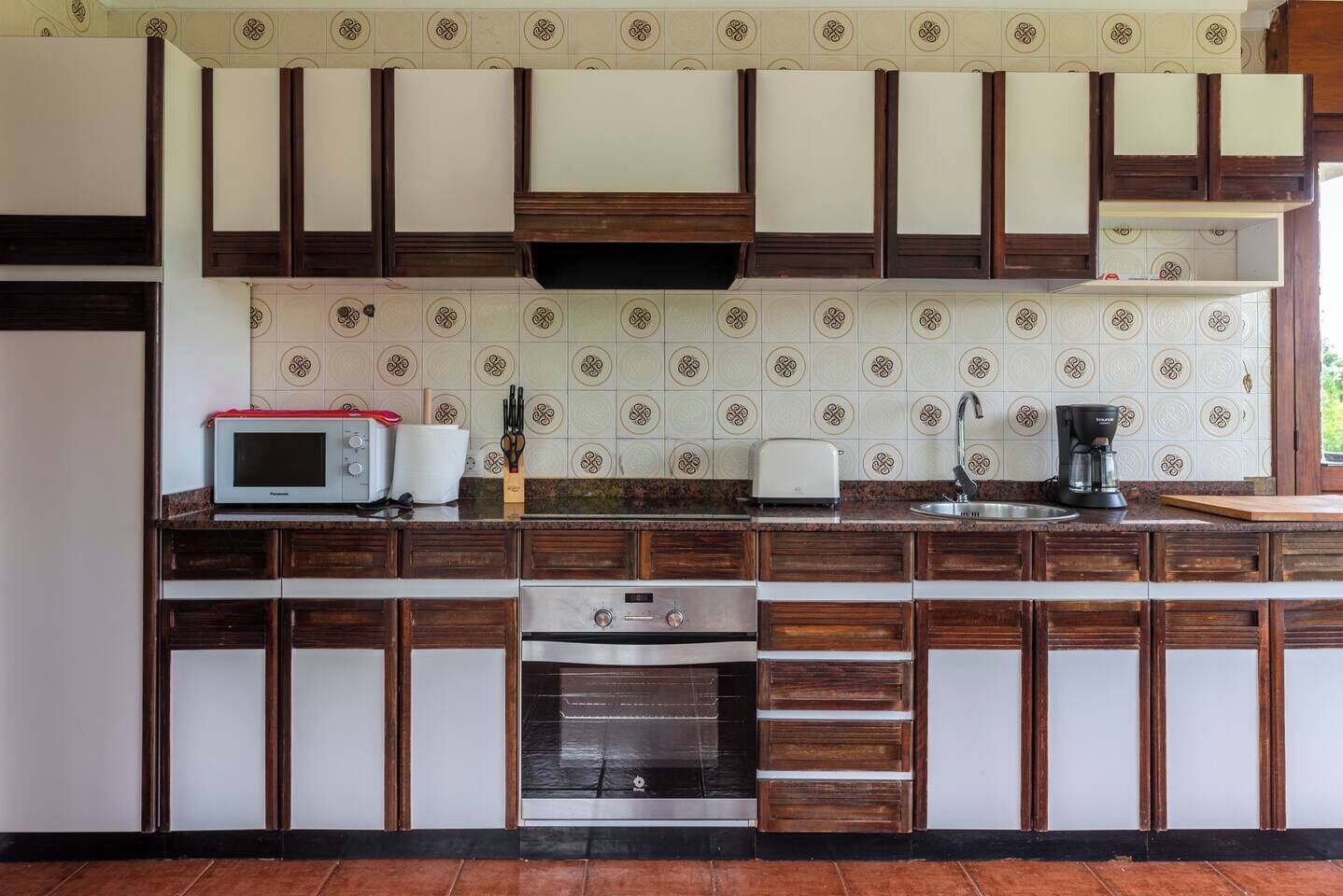 Une cuisine avec des meubles de rangement en bois, un four à micro-ondes, un grille-pain et une machine à café.