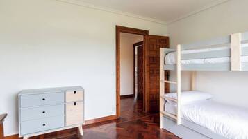 A room with a bunk bed, a dresser with drawers, and a wooden door.