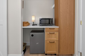 A compact kitchenette with a microwave, a small refrigerator, and a wooden cabinet. - Winter Park Lodge II Unit E102M Mt views hotel room outdoor pool & hot tub (Fraser)