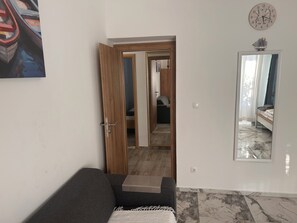 A room with a sofa, a mirror, a clock, and a door leading to another room. - Apartment Mediteran Okrug Gornji (Okrug Gornji)