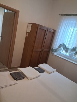 A room with a bed, a wooden wardrobe, a window with curtains, and a door. - Apartment Mediteran Okrug Gornji (Okrug Gornji)
