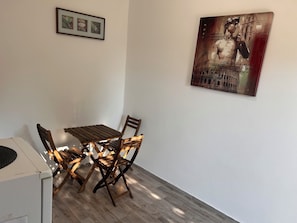 Ein Essbereich mit Holztisch und -stühlen, einer weißen Wand und einem gerahmten Bild über dem Tisch.