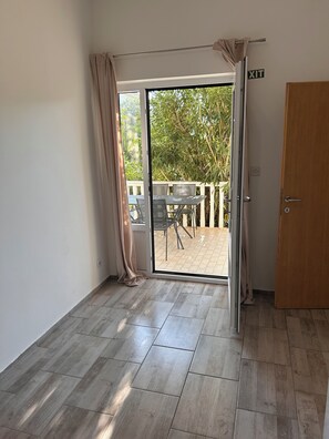 Ein Zimmer mit einer Schiebetür und Zugang zu einer Terrasse im Freien, komplett mit Tisch und Stühlen.