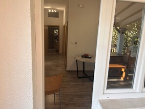 An interior space with a dining area, a wicker chair, and a table with a red object on it. - Apartment Mediteran Okrug Gornji (Okrug Gornji)