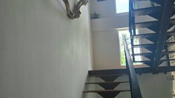 A staircase with wooden steps and a metal railing, leading to an upper floor.