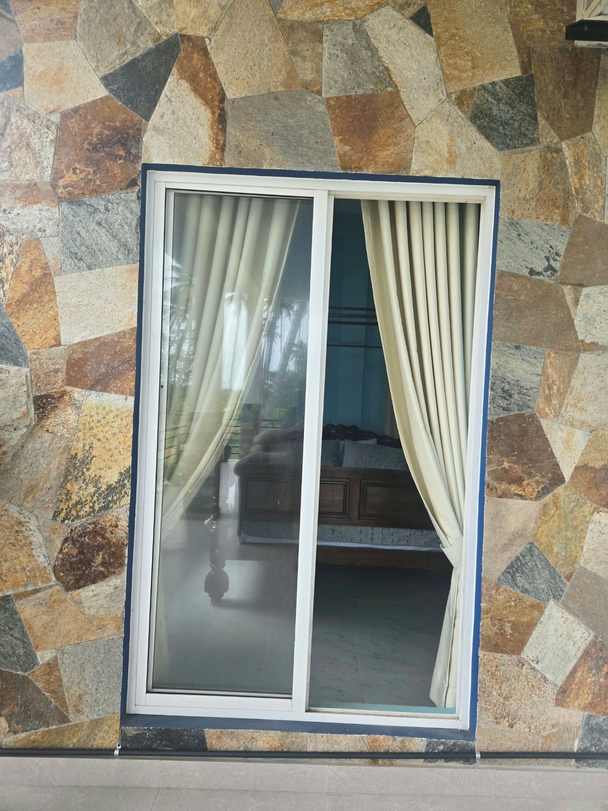 A window with a stone wall background and curtains.