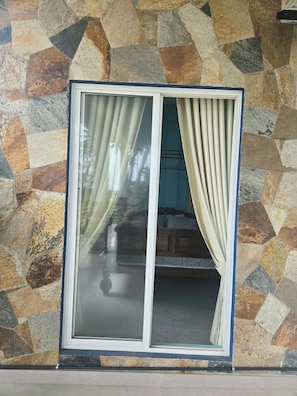 Una ventana con un muro de piedra y cortinas.