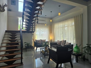 Una sala moderna con una escalera, un conjunto de sofás y una mesa de centro.