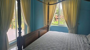 Una cama con dosel y un cabecero de madera en una habitación con paredes azules y cortinas blancas.