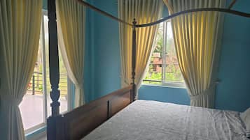 A four-poster bed with a wooden headboard in a room with blue walls and white curtains.