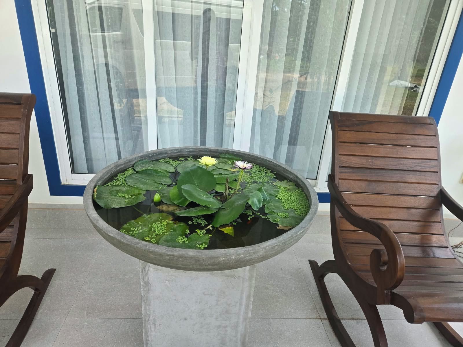 A round table with a water feature in the center, flanked by two wooden chairs.
