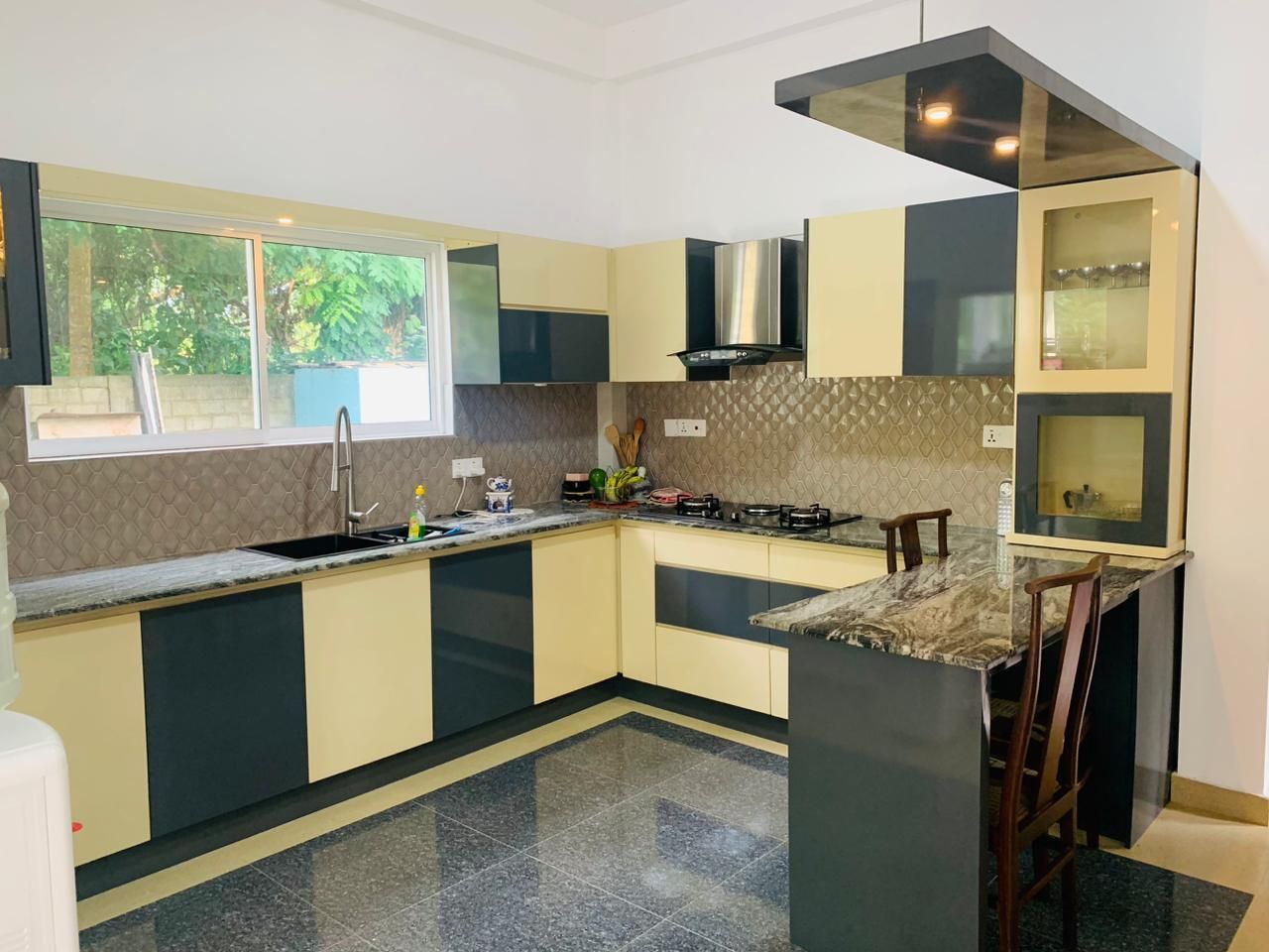 A modern kitchen with a central island, built-in appliances, and a large window providing natural light.