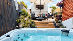 Ein Garten mit Whirlpool, Gartenmöbeln und Blumentöpfen.