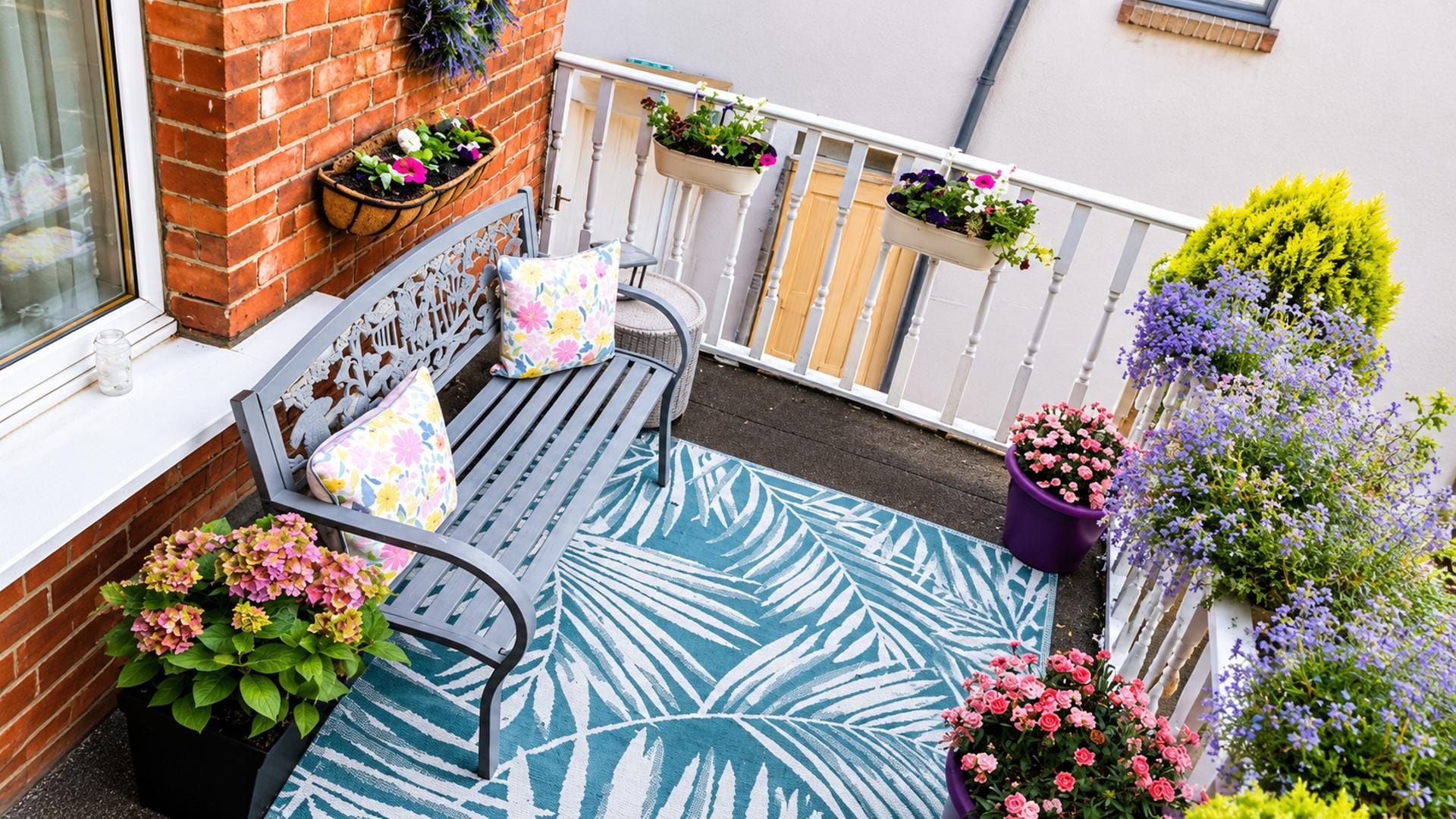 A balcony with a bench, potted plants, and a railing.