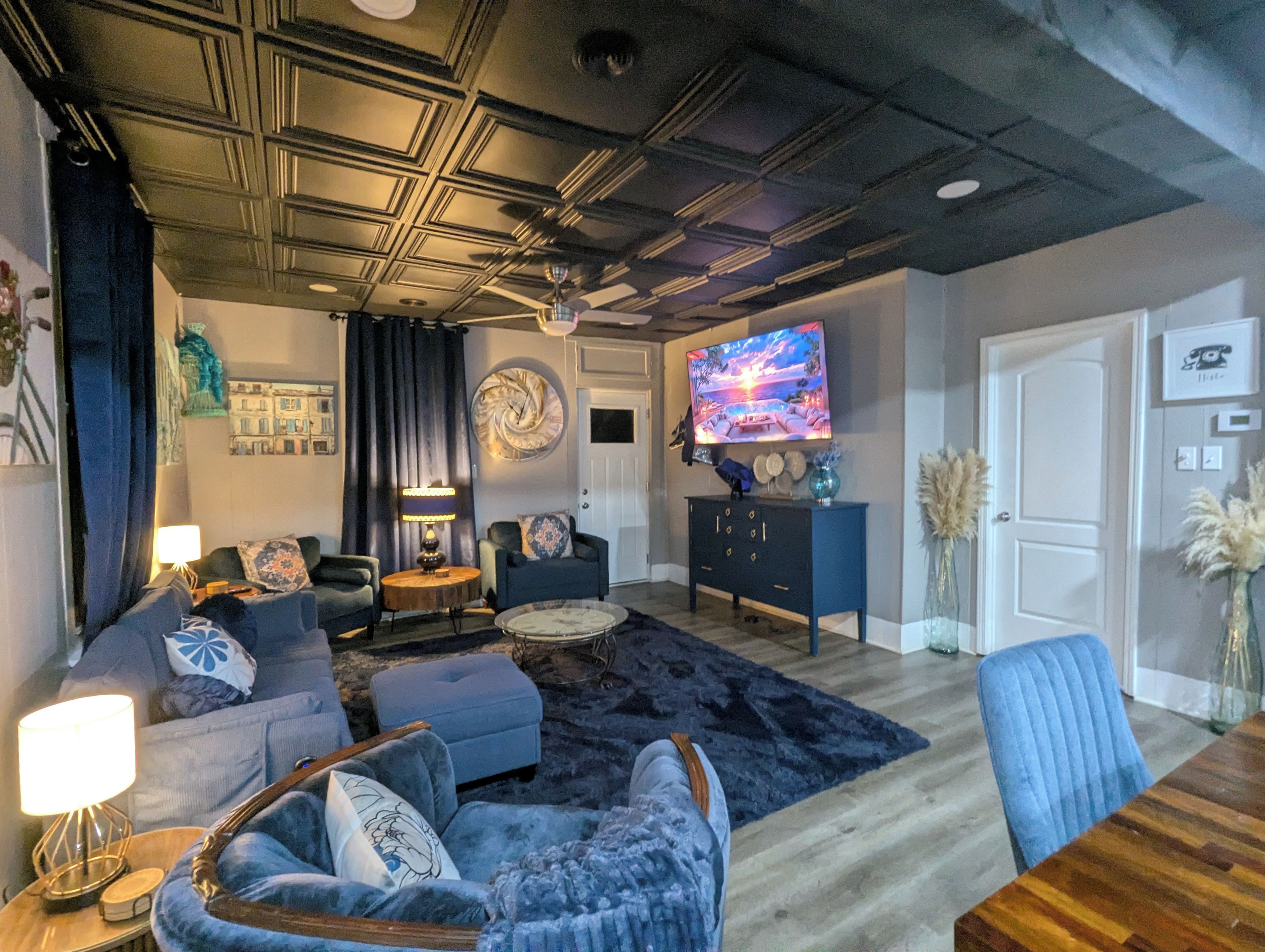 A modern living room with a sofa, armchairs, a coffee table, and a television.