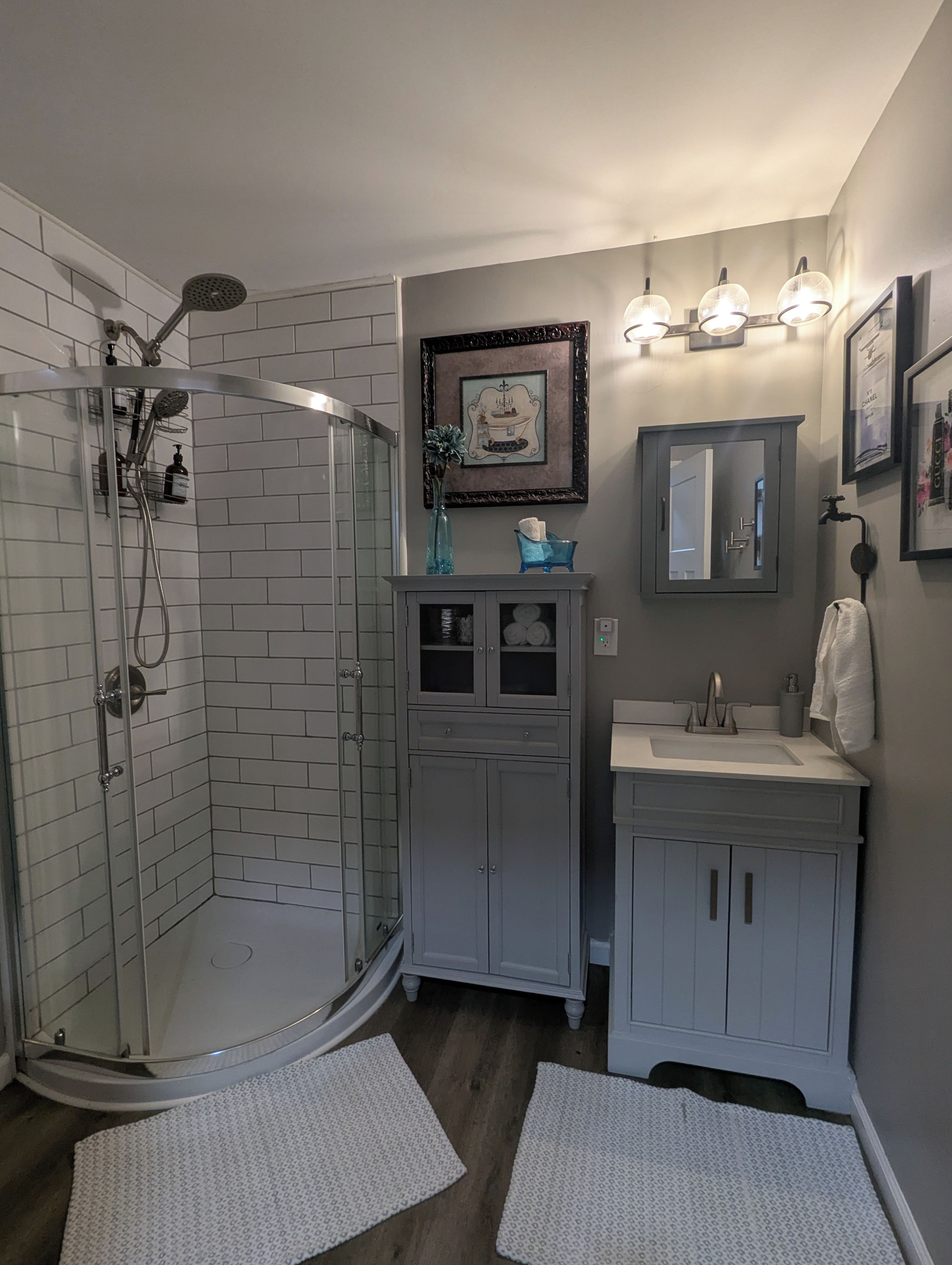 A bathroom with a shower, vanity, and a framed picture on the wall.