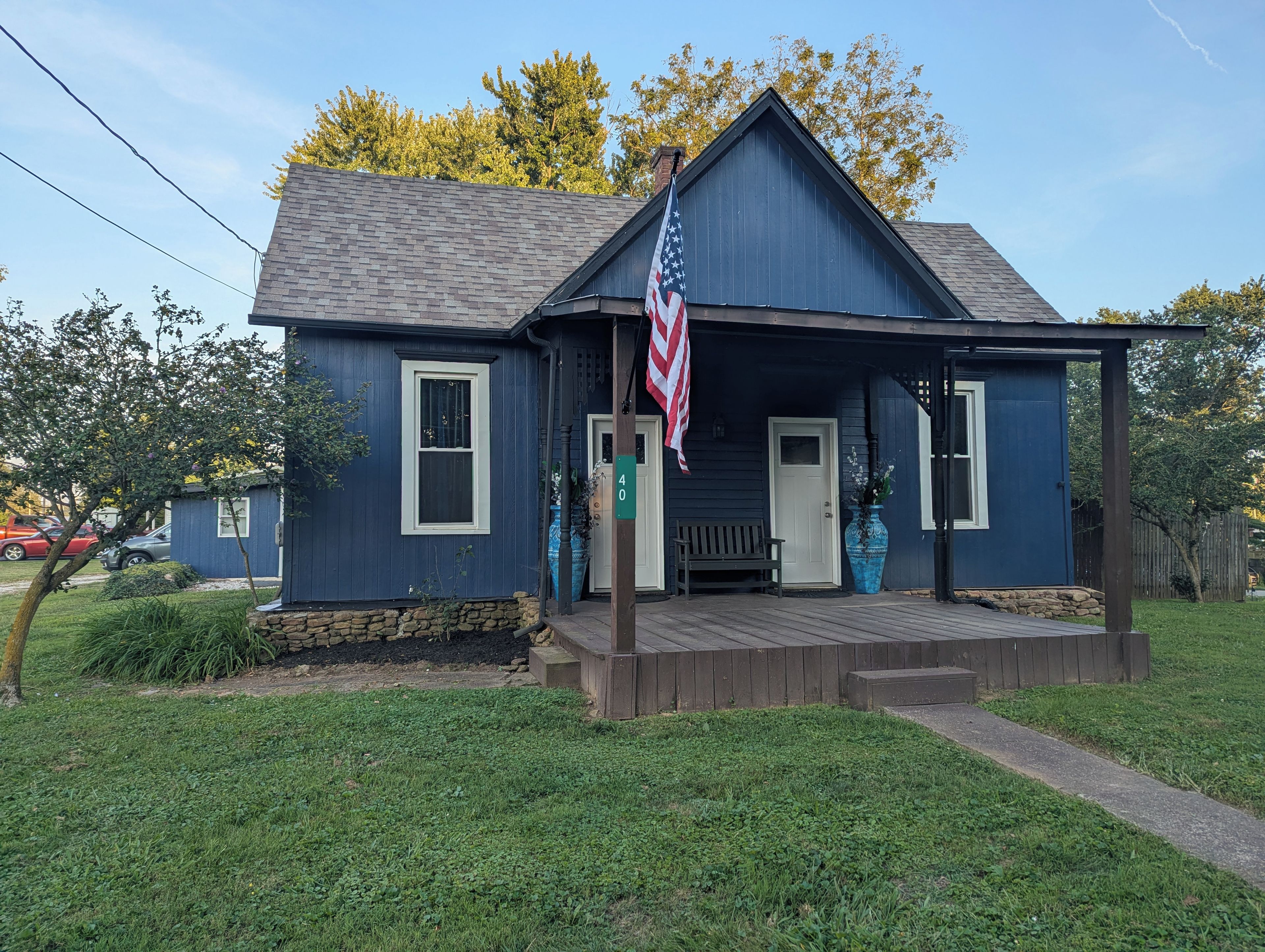 Une maison bleue avec un porche, un drapeau et une plaque portant le numéro 40.