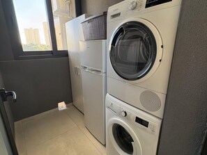 A compact laundry area with a front-loading washing machine, a dryer, and a refrigerator. - Spacious apartment, panoramic view - 6 guests (Benidorm)