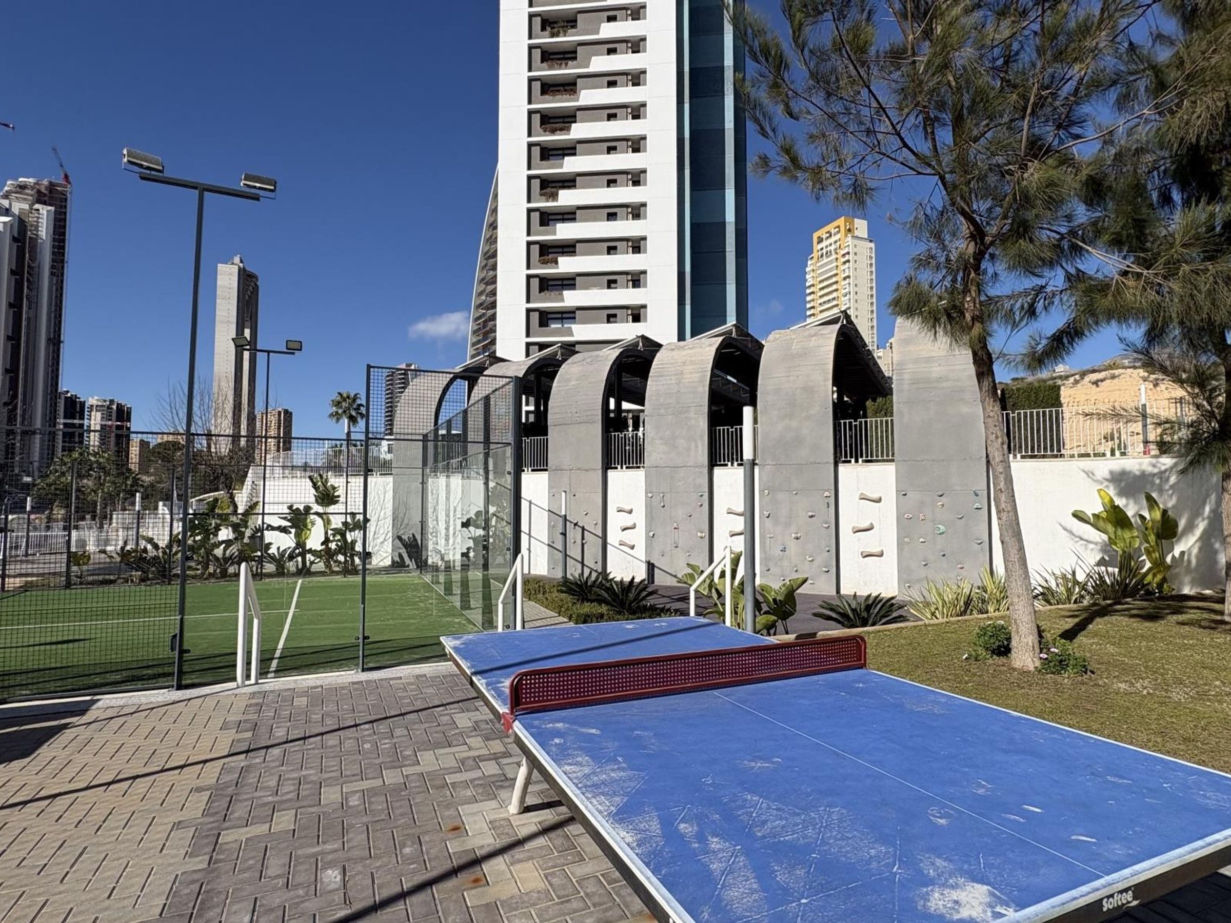 A ping pong table in an outdoor area with a modern building in the background.