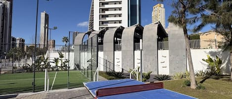 Une table de ping-pong installée dans un espace extérieur, avec un bâtiment moderne en arrière-plan.