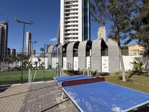 Een tafeltennistafel in een buitengebied met een modern gebouw op de achtergrond.