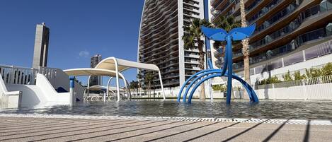 Een waterkantpromenade met moderne architectuur, waaronder hoge gebouwen en een opvallende blauwe sculptuur.